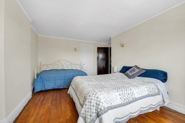 bedroom with baseboards, wood finished floors, and crown molding