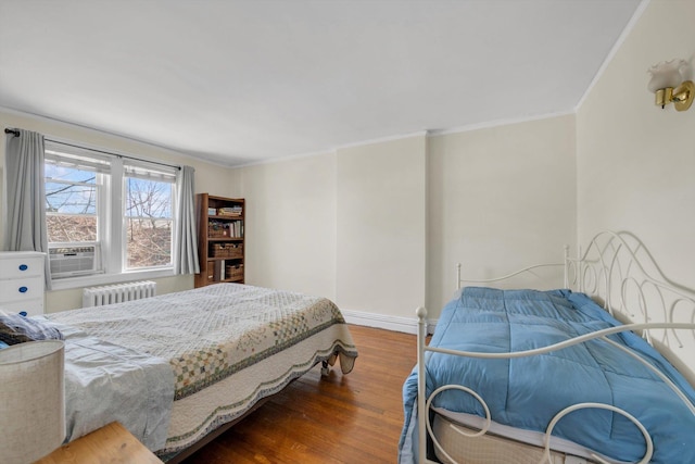 bedroom featuring baseboards, radiator, wood finished floors, and crown molding