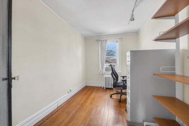 home office featuring hardwood / wood-style floors, baseboards, radiator heating unit, ornamental molding, and rail lighting