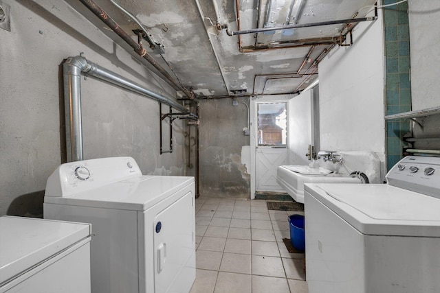 laundry area featuring washing machine and clothes dryer, laundry area, light tile patterned floors, and a sink