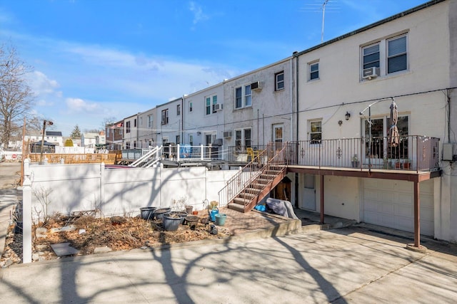 rear view of property featuring stucco siding, a residential view, concrete driveway, a garage, and stairs