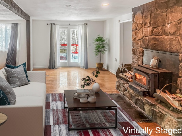 living area featuring a healthy amount of sunlight, a wood stove, and wood finished floors