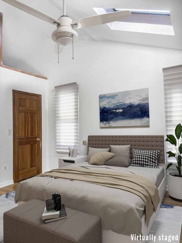 bedroom featuring a skylight, a ceiling fan, and wood finished floors