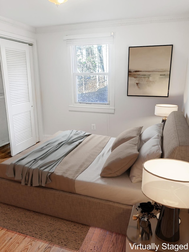 bedroom featuring wood finished floors, a closet, and ornamental molding