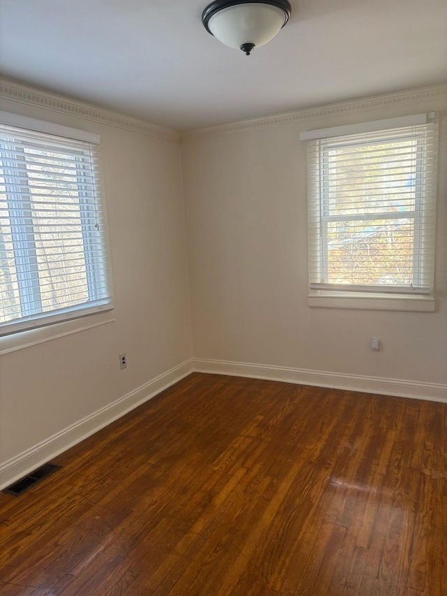 spare room with visible vents, baseboards, and dark wood finished floors