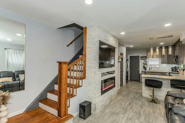 kitchen featuring recessed lighting, stainless steel appliances, light countertops, a kitchen bar, and light wood-type flooring