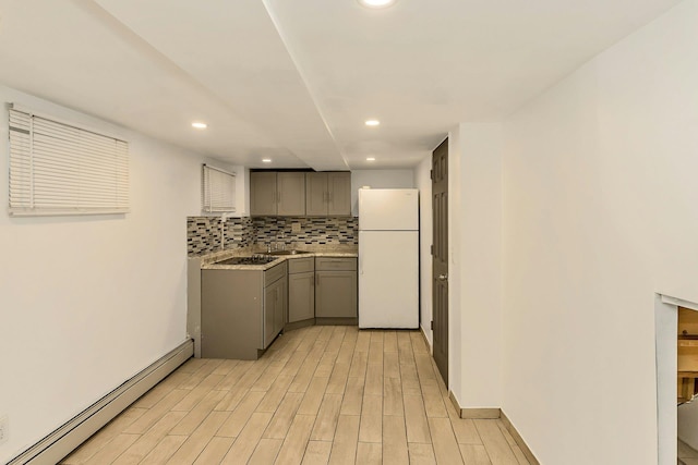 kitchen featuring light wood-type flooring, decorative backsplash, gray cabinets, freestanding refrigerator, and a baseboard radiator