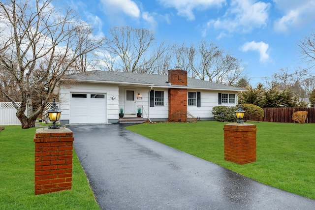 ranch-style home featuring fence, an attached garage, aphalt driveway, a front lawn, and a chimney