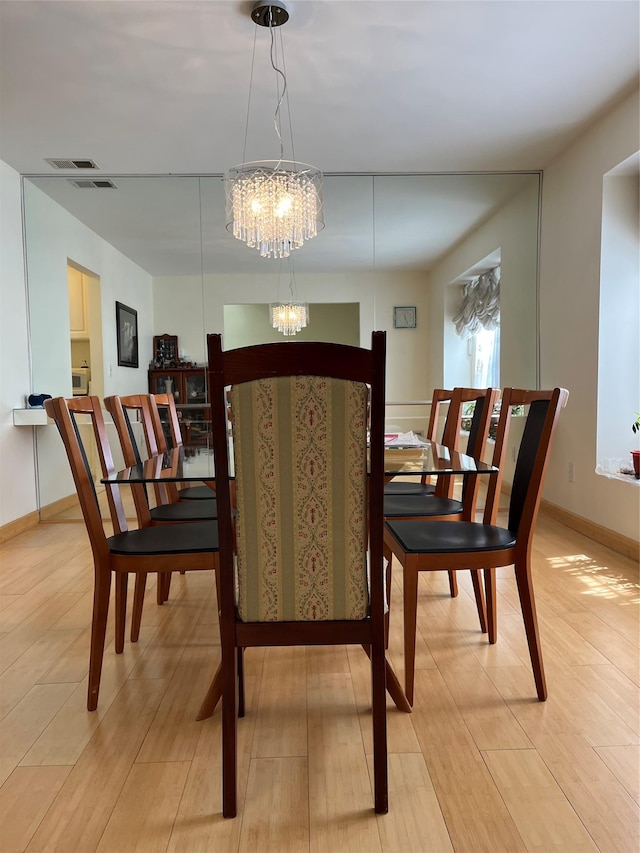 dining area featuring an inviting chandelier, visible vents, light wood-style flooring, and baseboards