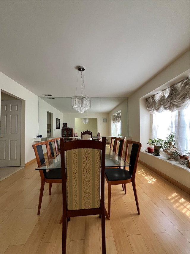 dining space featuring light wood-type flooring and a notable chandelier
