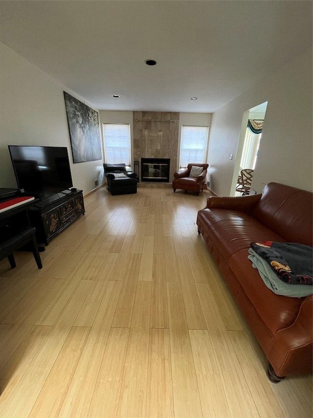 living room featuring light wood-type flooring, a tile fireplace, and plenty of natural light