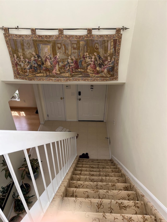 stairway with tile patterned floors and baseboards
