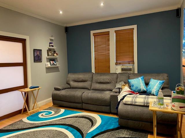 living room with baseboards, ornamental molding, recessed lighting, cooling unit, and wood finished floors