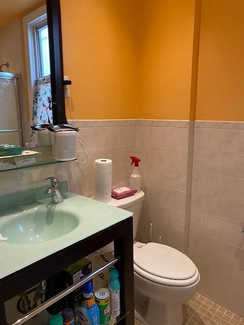 bathroom featuring wainscoting, toilet, tile walls, and vanity