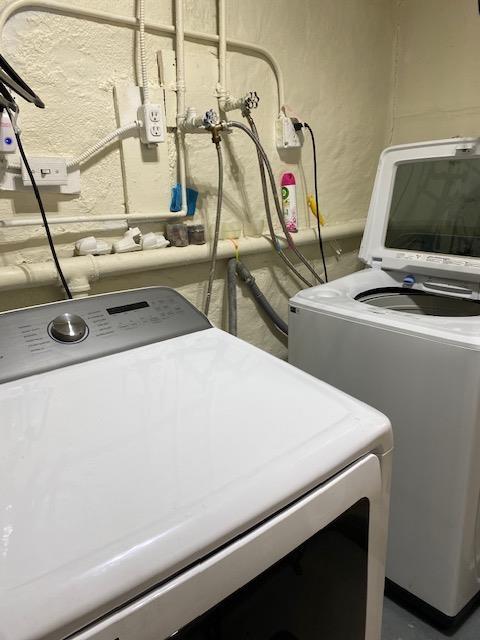 clothes washing area with independent washer and dryer and a textured wall