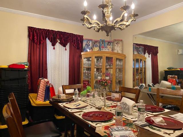 dining space with crown molding and an inviting chandelier