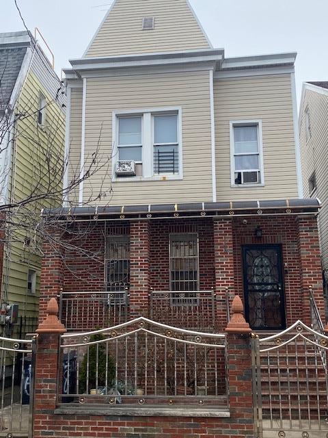 view of front of home featuring brick siding, covered porch, cooling unit, and a fenced front yard