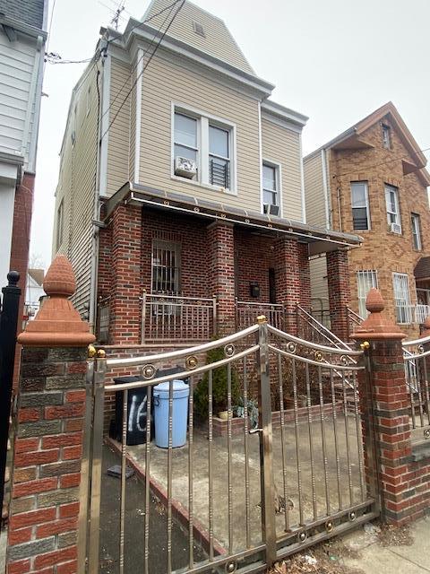 view of front facade with a fenced front yard, brick siding, covered porch, and a gate