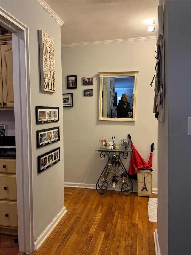 hallway with crown molding, wood finished floors, and baseboards