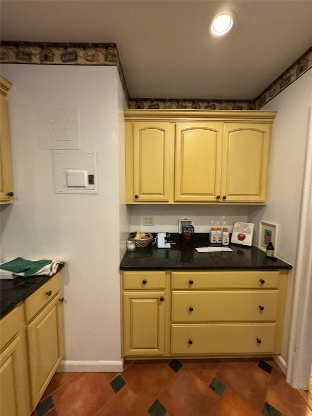 kitchen featuring dark countertops, baseboards, and dark tile patterned floors