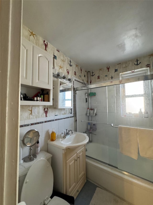 bathroom with enclosed tub / shower combo, toilet, tile walls, and vanity