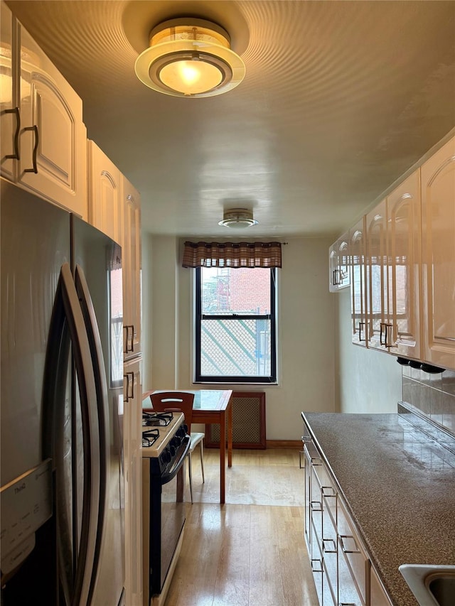 kitchen featuring light wood-style flooring, range with gas cooktop, and freestanding refrigerator