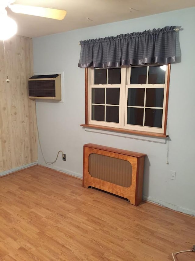 empty room with baseboards, wood finished floors, and a wall mounted AC