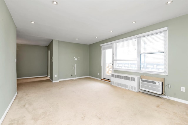 carpeted empty room with radiator, a wall unit AC, baseboards, and recessed lighting