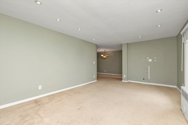 empty room featuring light carpet, a notable chandelier, baseboards, and recessed lighting