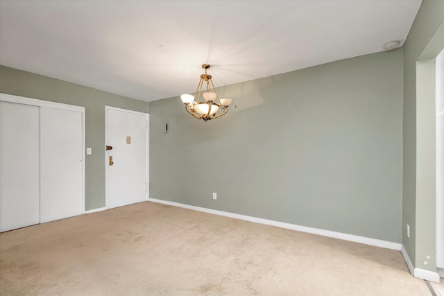 empty room with a chandelier, light colored carpet, and baseboards