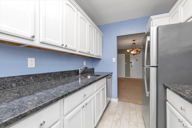 kitchen with dark stone countertops, white cabinetry, a sink, and appliances with stainless steel finishes