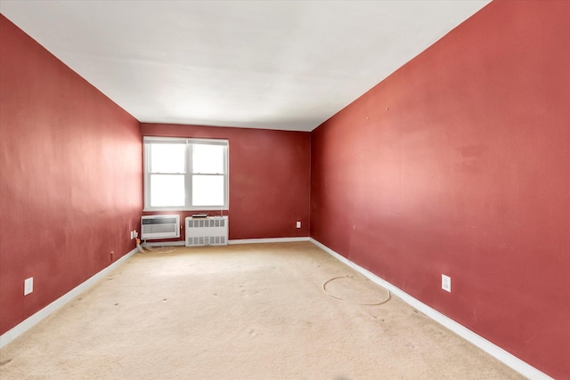 carpeted empty room featuring baseboards and a wall unit AC