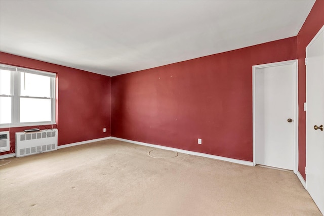 carpeted empty room with radiator and baseboards