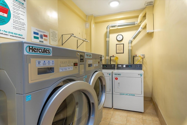 community laundry room with washing machine and dryer, baseboards, and light tile patterned flooring