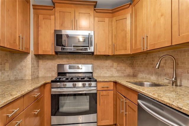 kitchen featuring light stone counters, a sink, backsplash, and appliances with stainless steel finishes