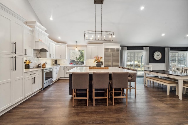 kitchen featuring a breakfast bar, tasteful backsplash, a kitchen island, appliances with stainless steel finishes, and white cabinets