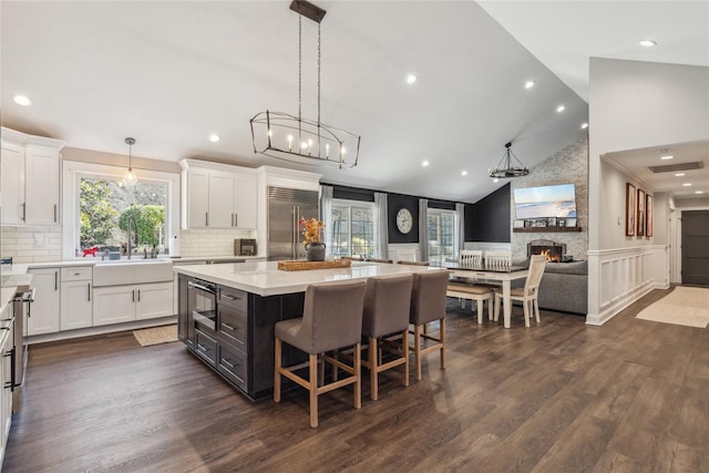 kitchen featuring a stone fireplace, white cabinets, and stainless steel built in fridge