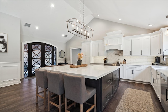 kitchen with a breakfast bar, visible vents, white cabinetry, and light countertops