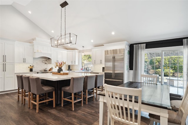 dining space featuring high vaulted ceiling, recessed lighting, dark wood-style flooring, and a chandelier