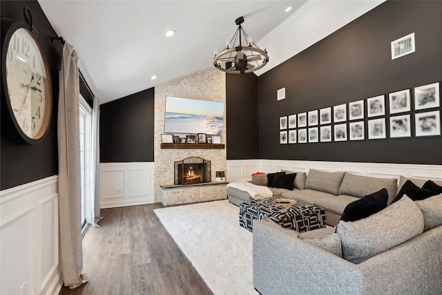 living room featuring visible vents, lofted ceiling, wainscoting, an inviting chandelier, and wood finished floors