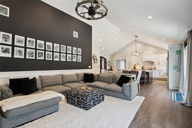 living area with visible vents, a wainscoted wall, high vaulted ceiling, a chandelier, and dark wood-style flooring