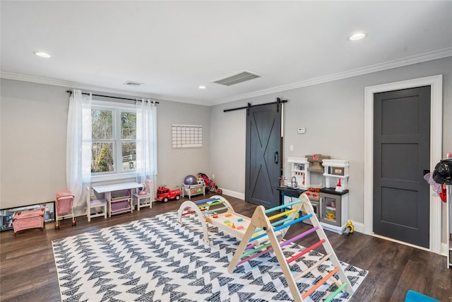 recreation room featuring a barn door, visible vents, wood finished floors, and ornamental molding