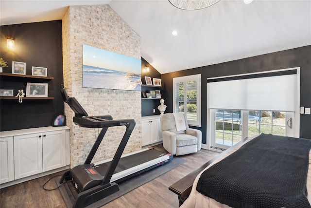 bedroom with high vaulted ceiling and wood finished floors