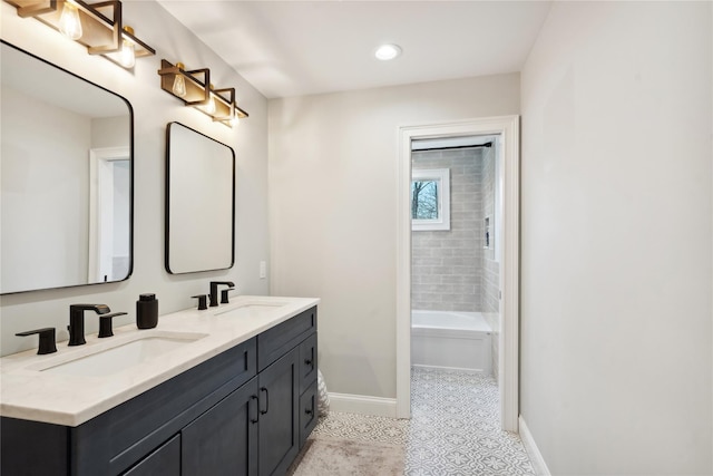 full bath featuring double vanity, a tub, baseboards, and a sink