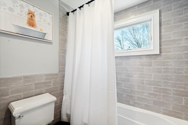 bathroom with shower / bathtub combination with curtain, toilet, and tile walls