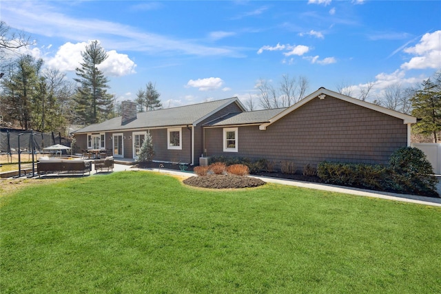 rear view of property featuring a lawn, a patio, central AC, fence, and a chimney