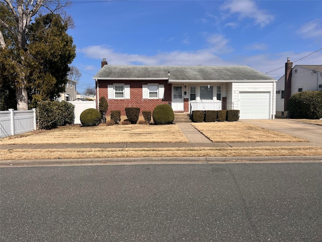 view of front of home with a porch, fence, concrete driveway, a garage, and a chimney