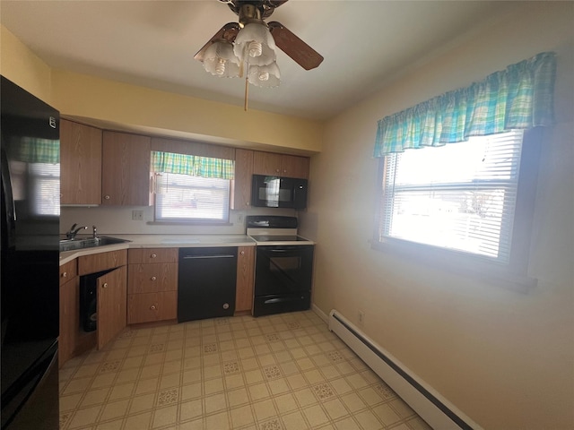 kitchen with a sink, a baseboard heating unit, black appliances, and a wealth of natural light