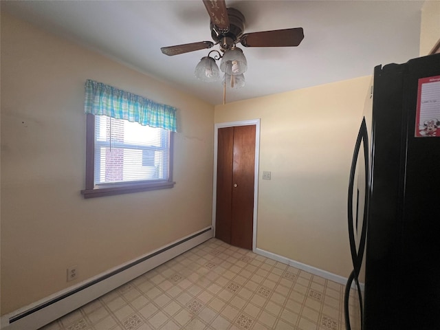 kitchen featuring a baseboard heating unit, baseboards, light floors, freestanding refrigerator, and a ceiling fan