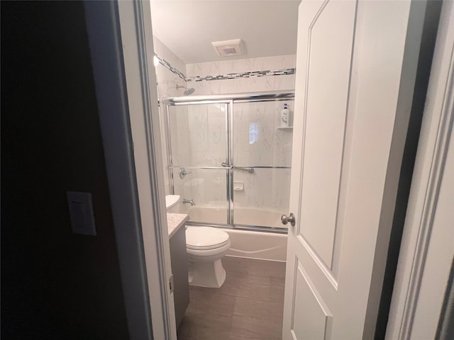 bathroom featuring enclosed tub / shower combo, visible vents, toilet, and vanity